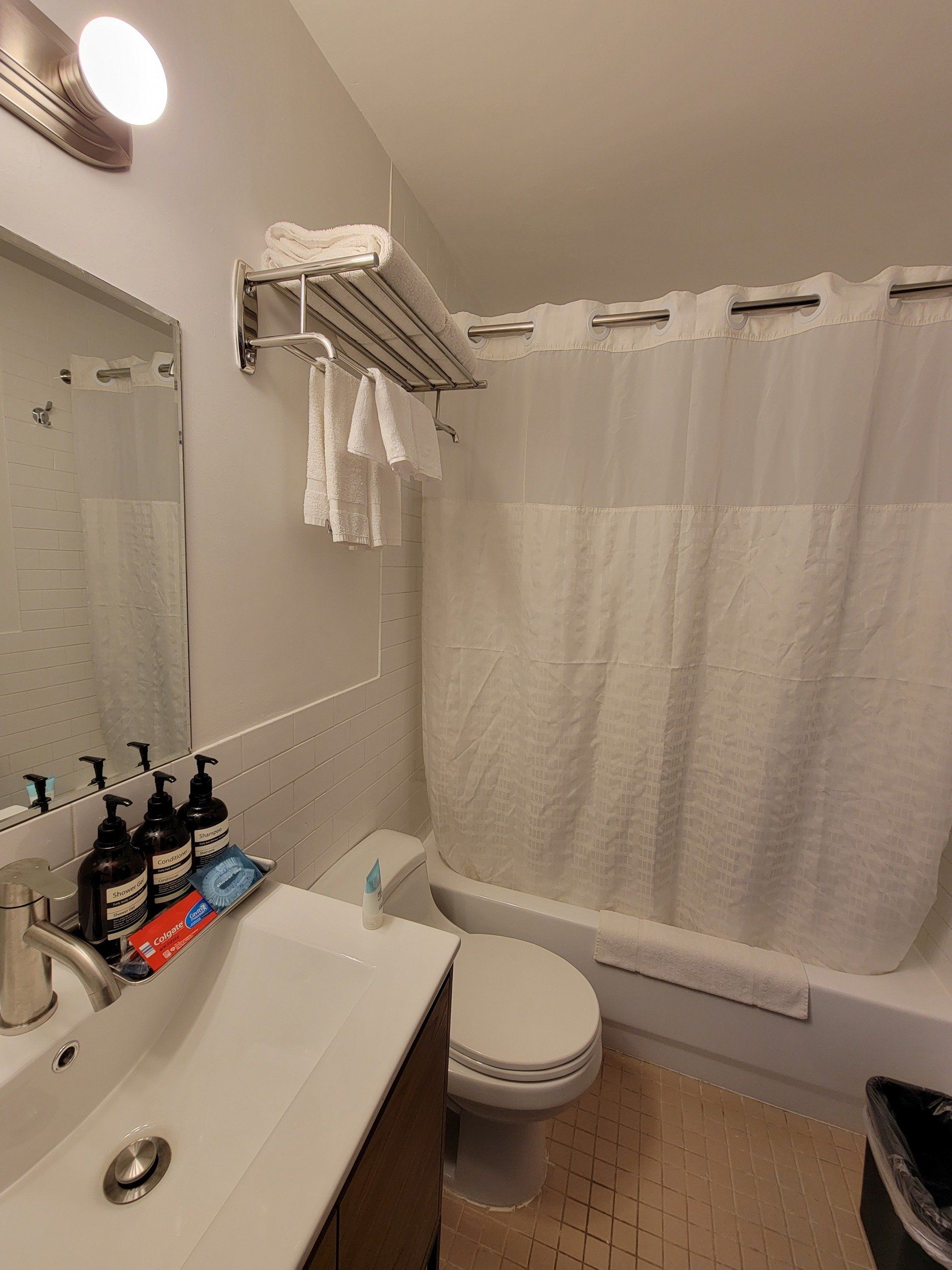 A bathroom with a sink , toilet , shower and mirror.