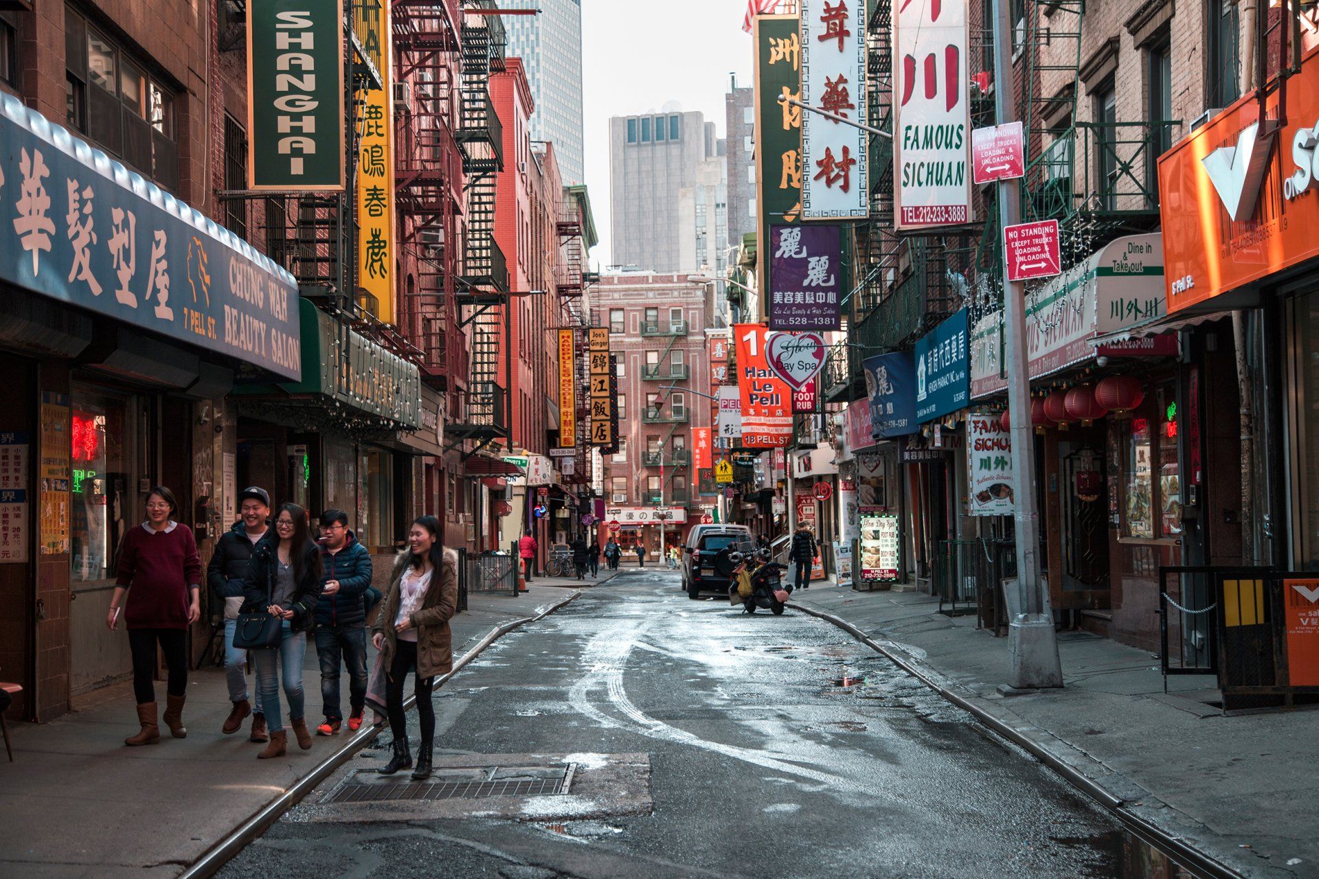 A group of people are walking down an empty street in a city.