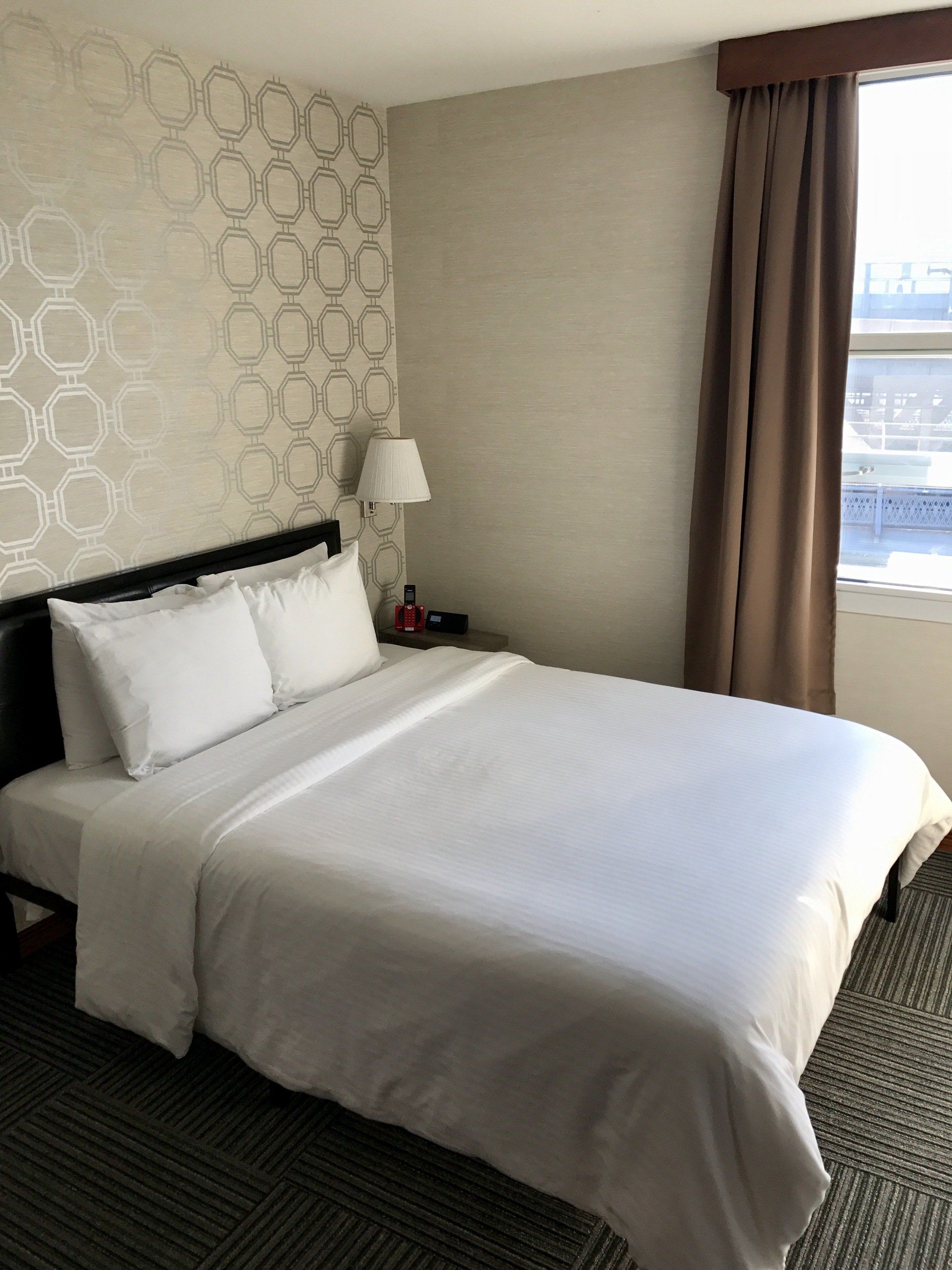 A hotel room with a bed and a lamp