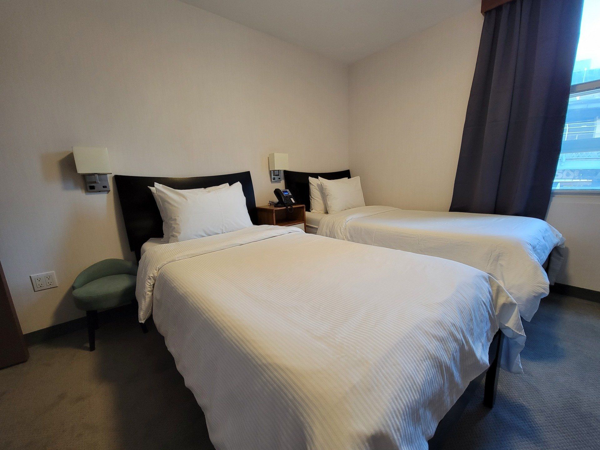 A hotel room with two twin beds and a chair.