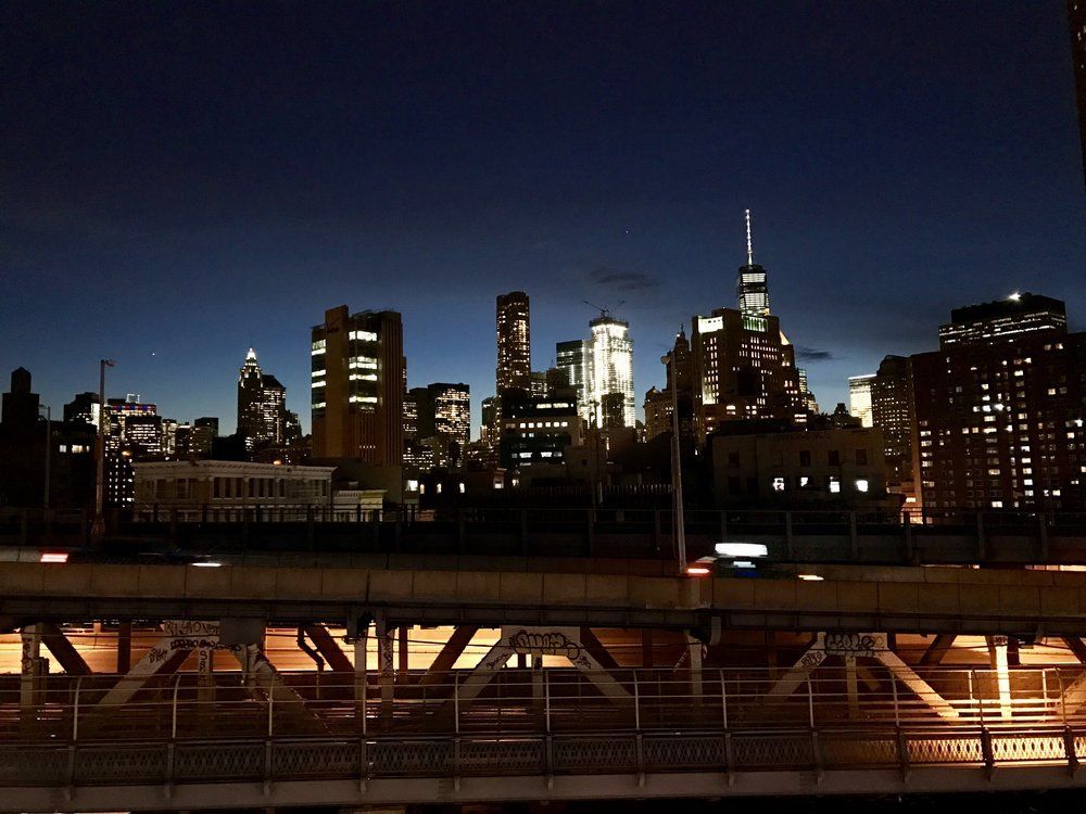 A city skyline at night with a bridge in the foreground