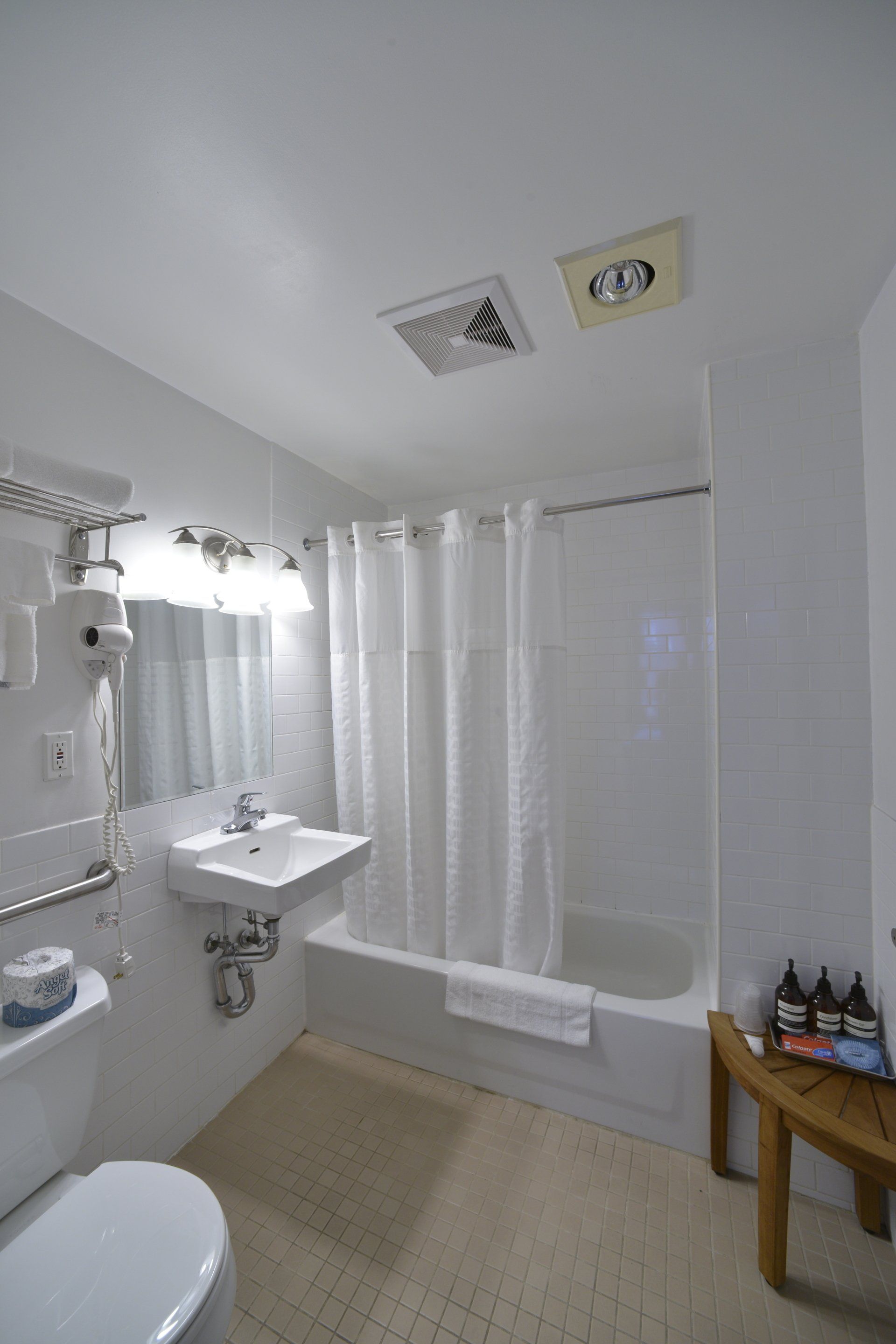 A bathroom with a toilet , sink , tub and mirror.