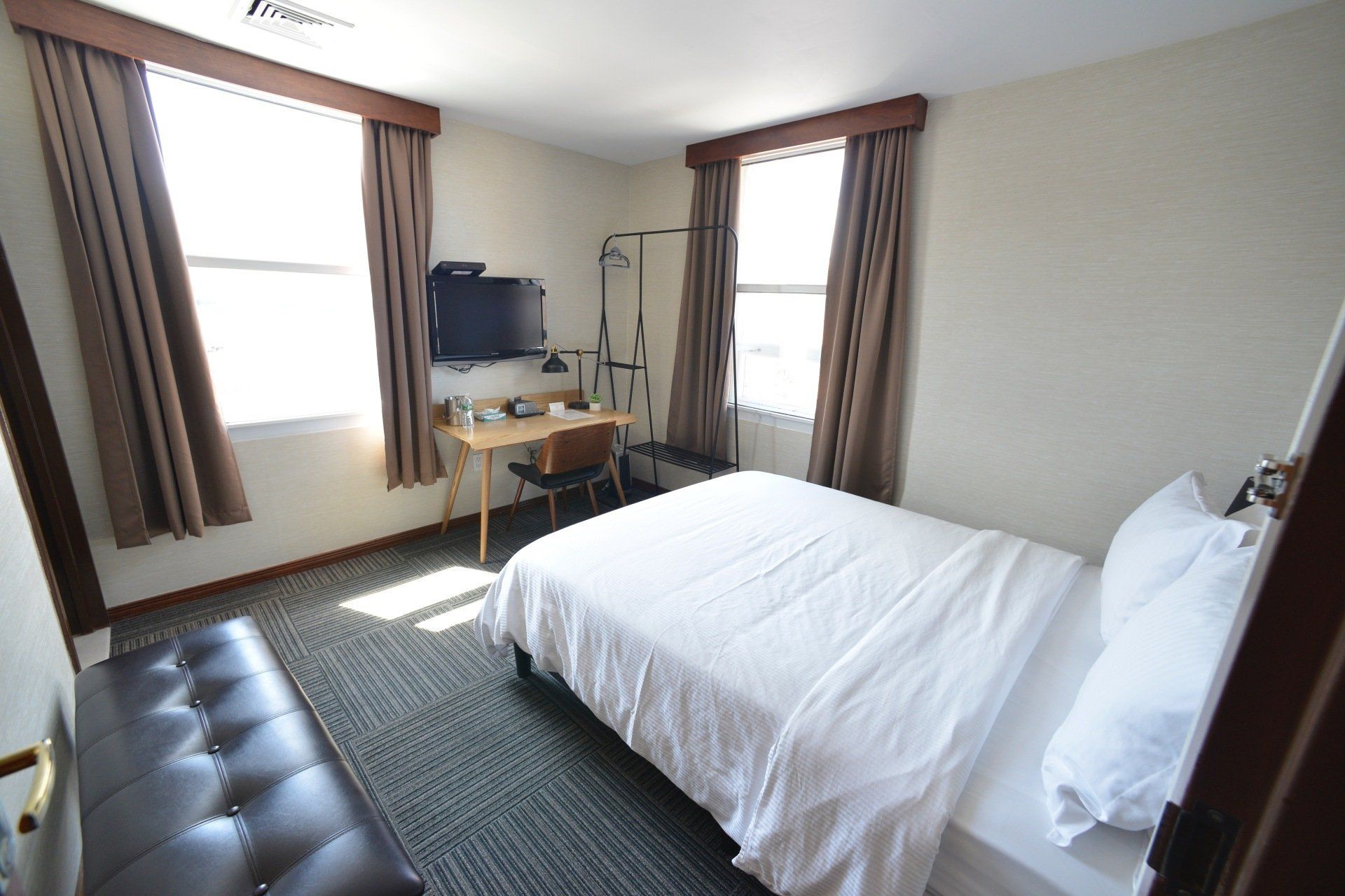 A hotel room with a bed , desk and television.