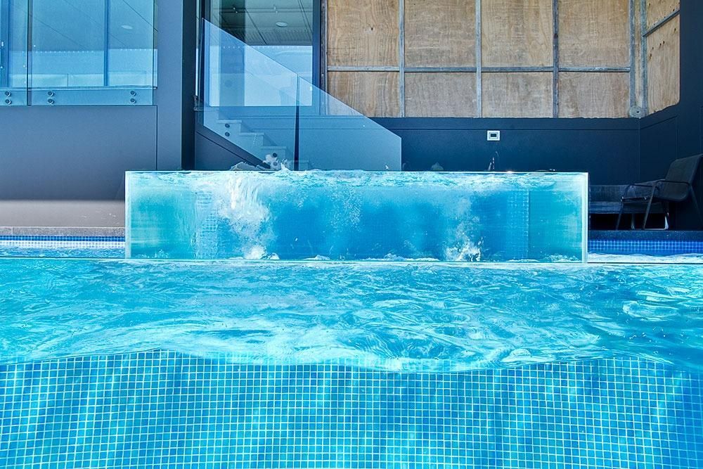 A Swimming Pool With A Waterfall In The Middle Of It — Dimension One Glass Fencing In Tuggerah, NSW