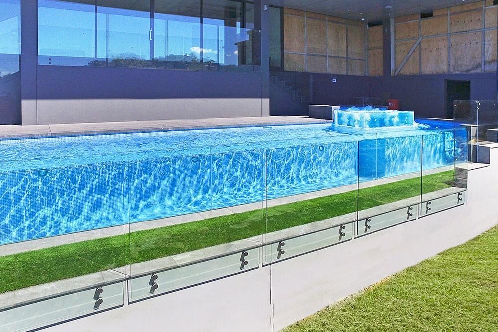 A large swimming pool is surrounded by a glass fence — Dimension One Glass Fencing In Tuggerah, NSW