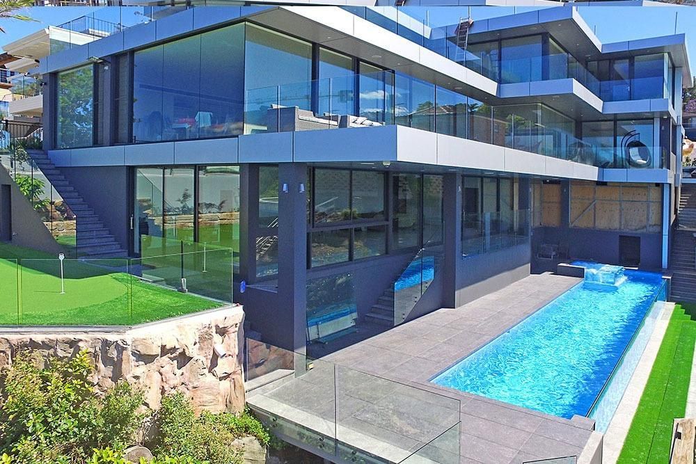 A Large House With A Swimming Pool In Front Of It — Dimension One Glass Fencing In Tuggerah, NSW