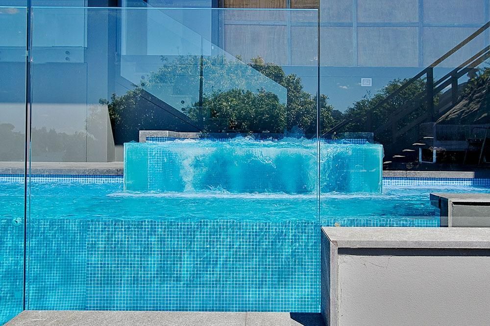 A Swimming Pool With A Waterfall In The Middle Of It — Dimension One Glass Fencing In Tuggerah, NSW