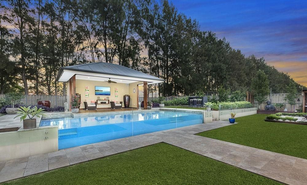 There Is A Large Swimming Pool In The Backyard Of A House — Dimension One Glass Fencing In Tuggerah, NSW