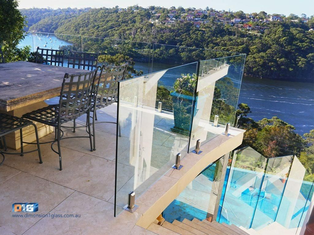 A Table And Chairs On A Glass Fenced Balcony Overlooking A Body Of Water — Dimension One Glass Fencing In Tuggerah, NSW
