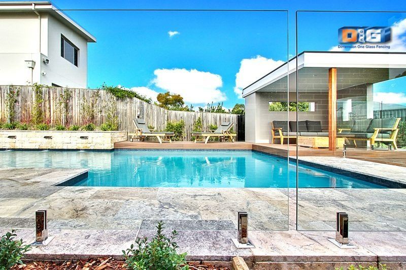 A Large Swimming Pool Is Surrounded By A Glass Fence — Dimension One Glass Fencing In Tuggerah, NSW