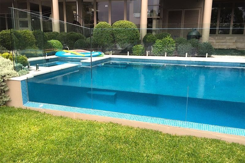 A Large Swimming Pool With A Clear Glass Fence In The Backyard Of A House — Dimension One Glass Fencing In Hunter Valley, NSW