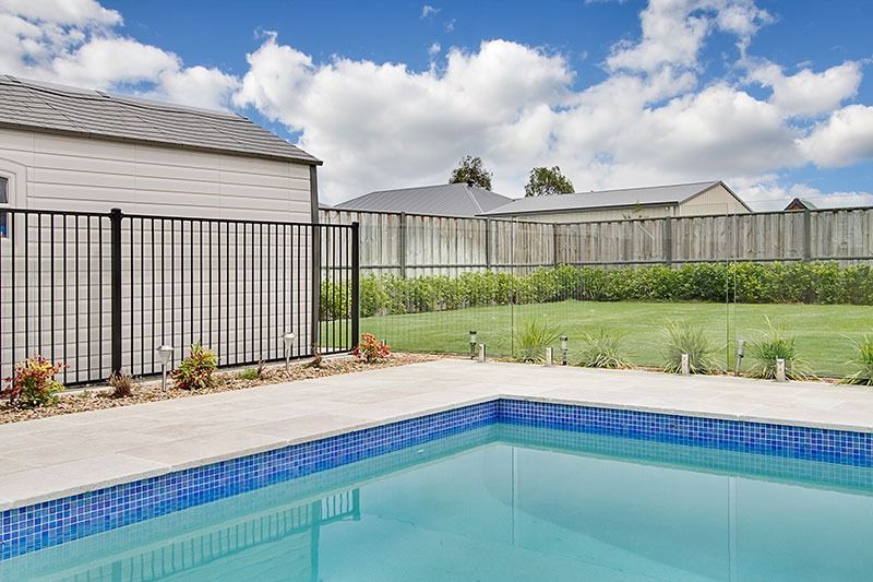 A Swimming Pool With A Fence Around It And A House In The Background — Dimension One Glass Fencing In Newcastle, NSW