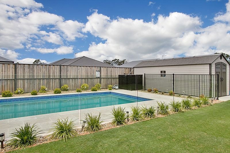 There Is A Large Swimming Pool In The Backyard Of A House — Dimension One Glass Fencing In Newcastle, NSW