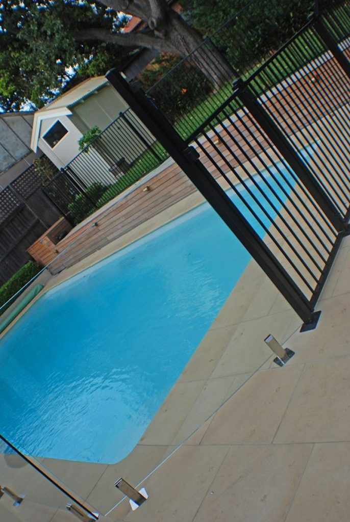 A Fence Surrounds A Swimming Pool — Dimension One Glass Fencing In Newcastle, NSW