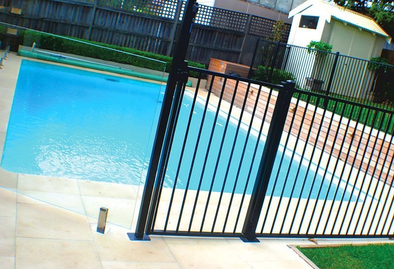 A Black Fence Surrounds A Large Swimming Pool — Dimension 1 Glass Fencing In Newcastle, NSW