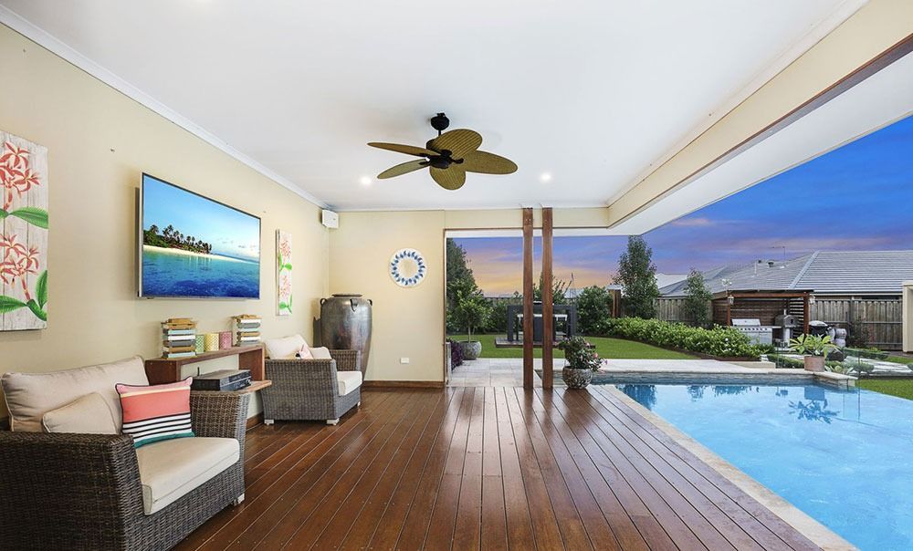 A Living Room With A Ceiling Fan And A Swimming Pool — Dimension One Glass Fencing In Tuggerah, NSW