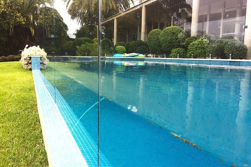 A Large Swimming Pool With A Clear Glass Fence Around It — Dimension One Glass Fencing In Central Coast, NSW