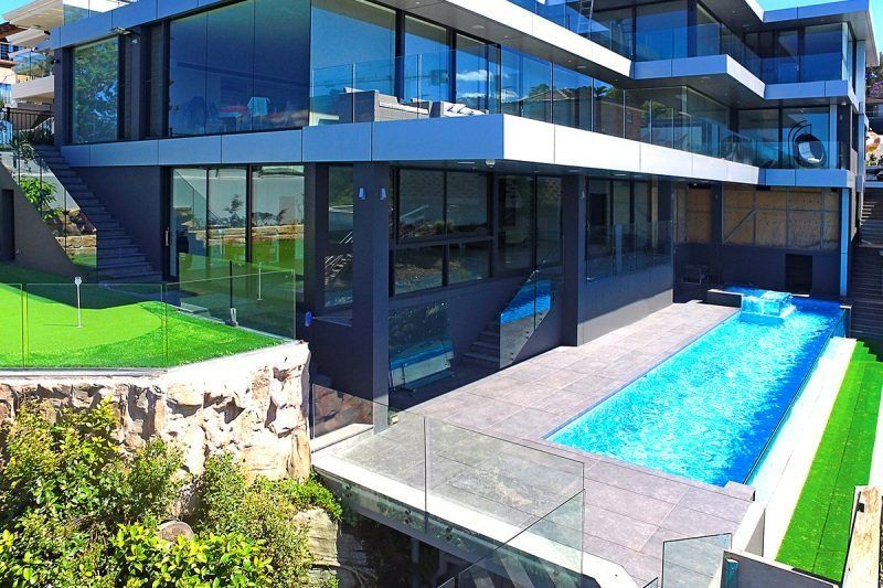 A Large House With A Swimming Pool In Front Of It — Dimension One Glass Fencing In Central Coast, NSW