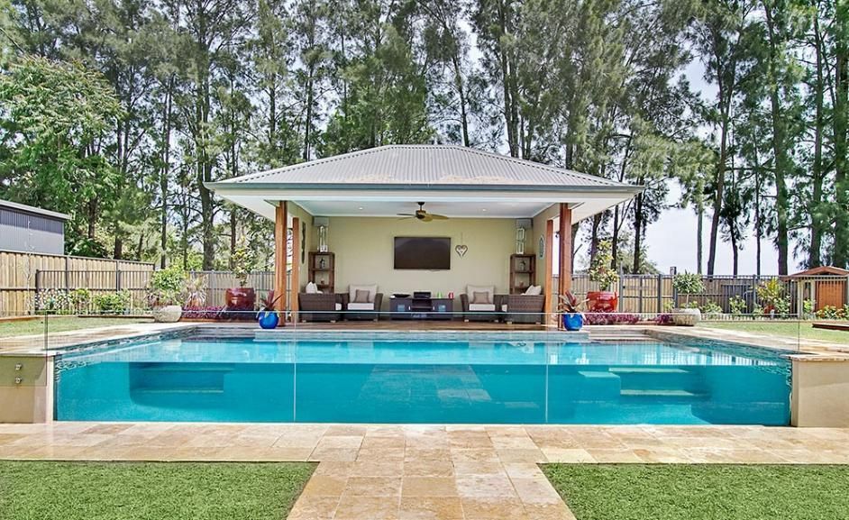 A Large Swimming Pool is Surrounded by Trees and a Gazebo — Dimension One Glass Fencing in Port Stephens, NSW