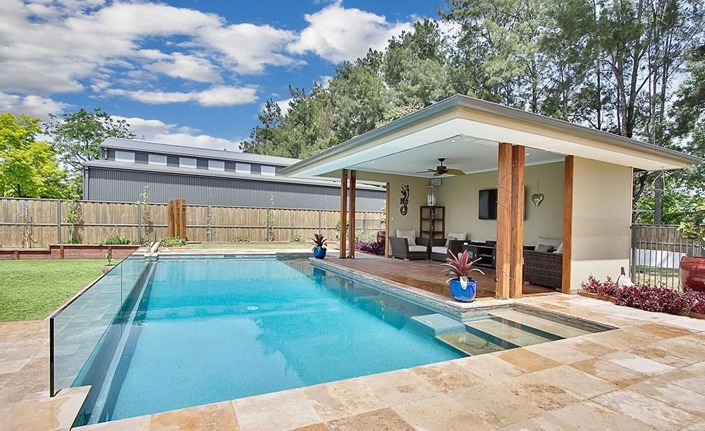A Large Swimming Pool With A Gazebo In The Backyard — Dimension One Glass Fencing In Tuggerah, NSW