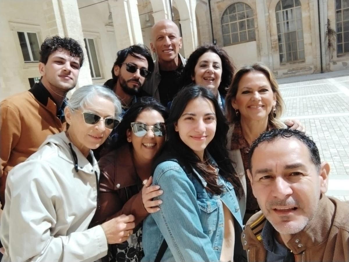 Gruppo di persone sorridenti per una foto, all'aperto nel cortile di un edificio.