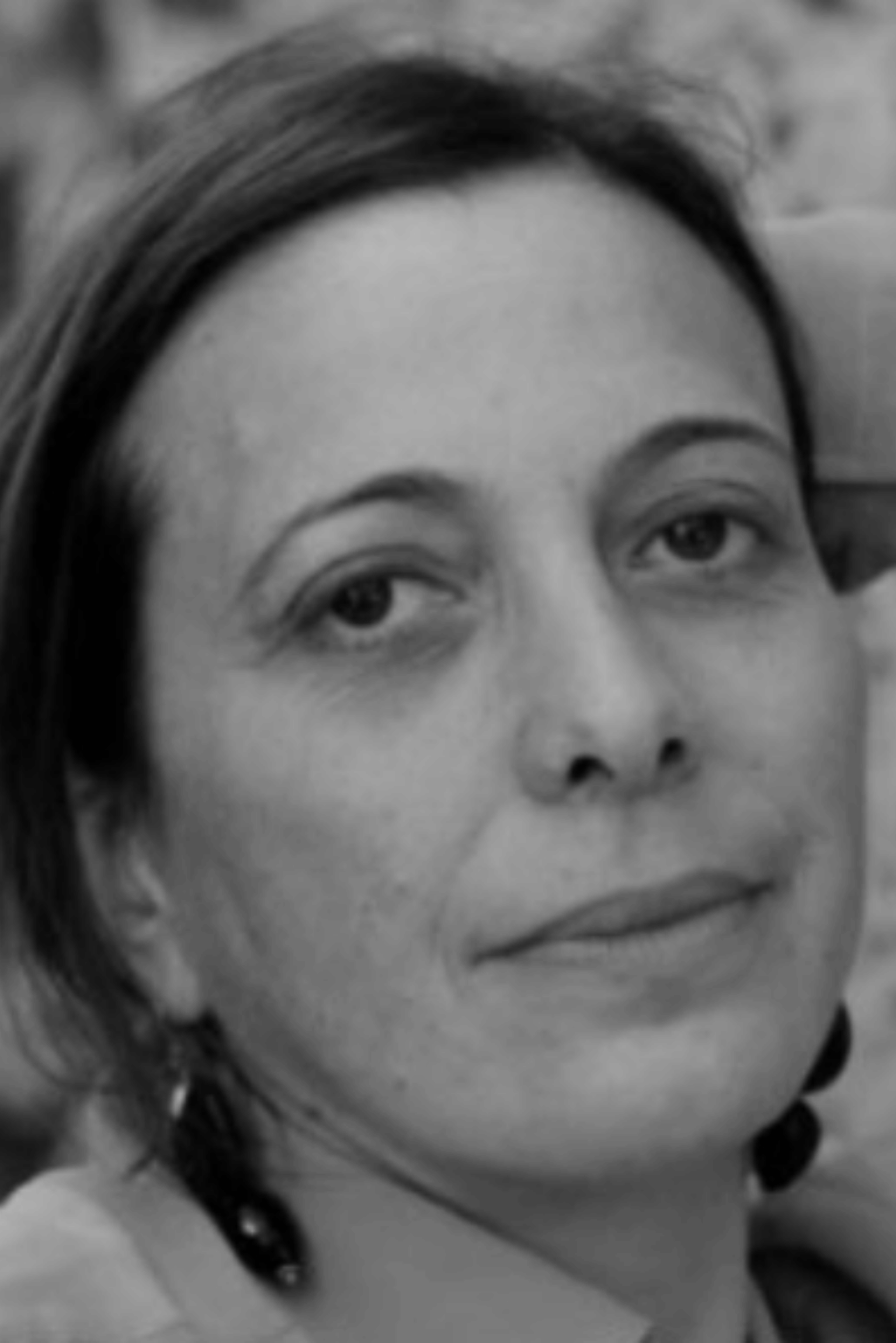 Donna che guarda verso la telecamera, fotografia in bianco e nero, leggero sorriso, espressione neutra.