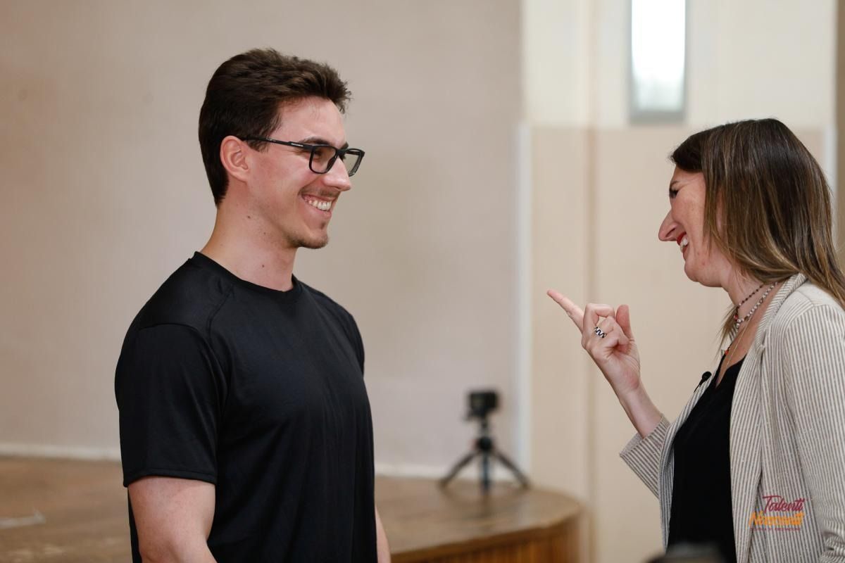 L'uomo sorride e guarda la donna che gli punta il dito. Sono in casa.