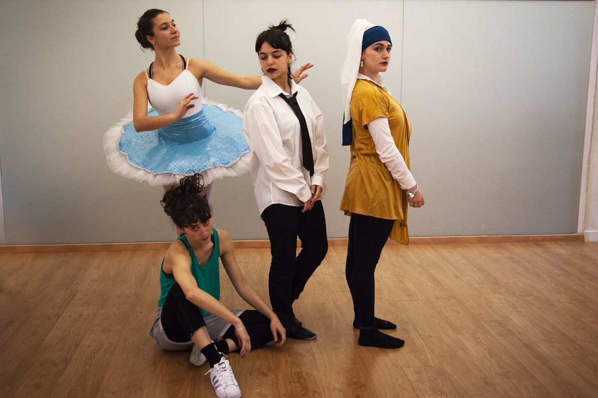 Quattro persone in costume: una ballerina, una donna in costume, la ragazza con l'orecchino di perla e un'altra in abbigliamento sportivo, in una sala da ballo.