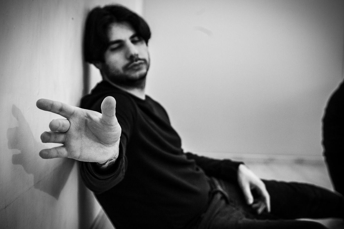 Uomo appoggiato al muro, braccio teso. Foto in bianco e nero.