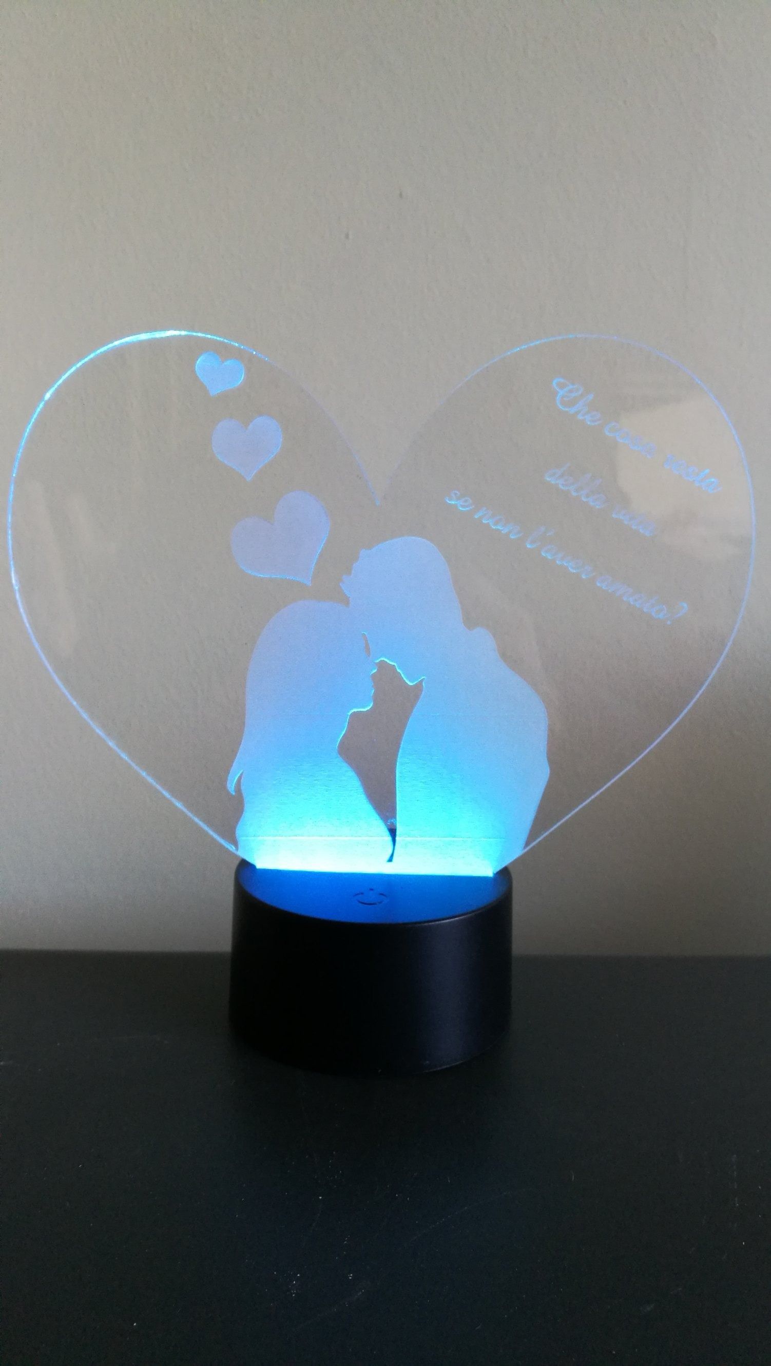 Luce notturna a forma di cuore con la sagoma di una coppia che si bacia, luminosa di blu.