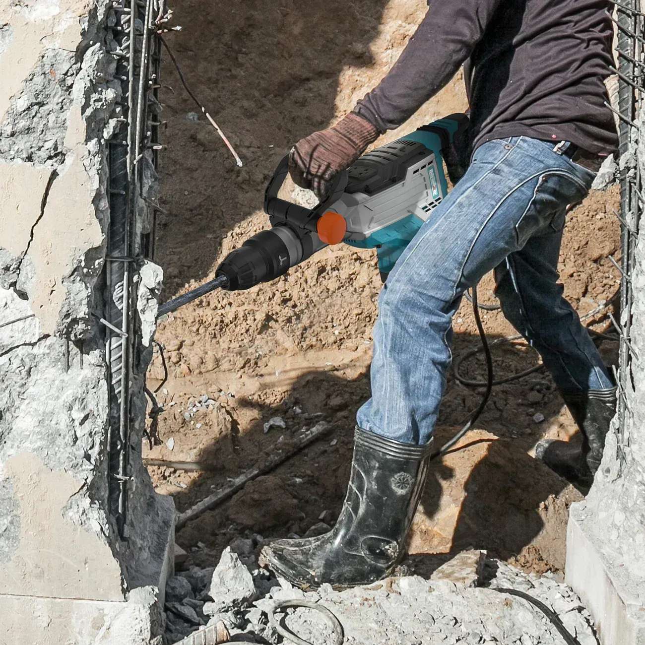 A man is using a hammer to break a concrete wall