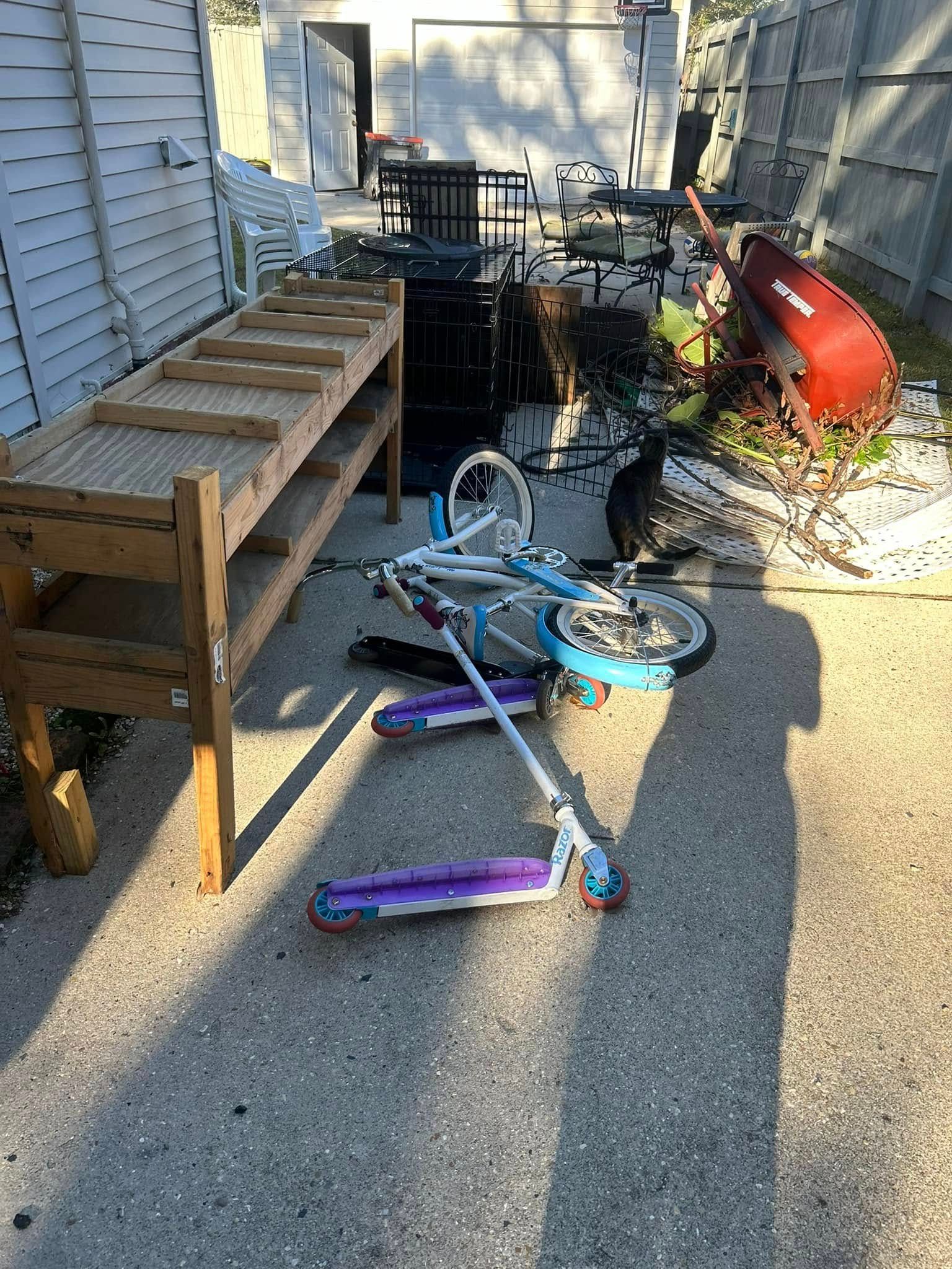 A bicycle and scooter are sitting on the ground in a backyard.