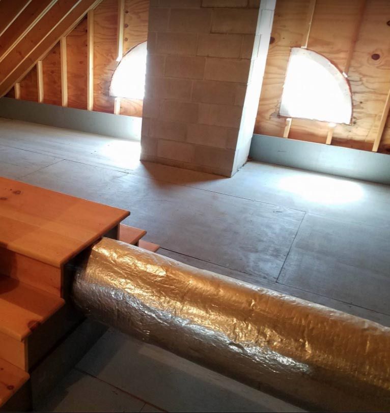 An attic with a wooden table and a metal pipe