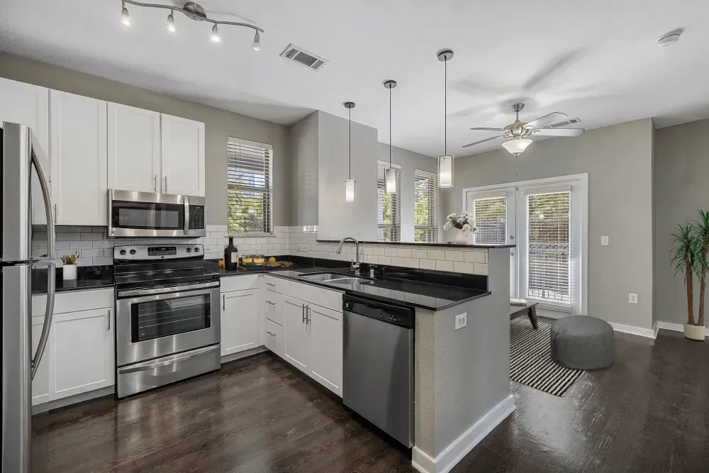 Modern kitchen with white cabinets, stainless steel appliances, and dark countertops.