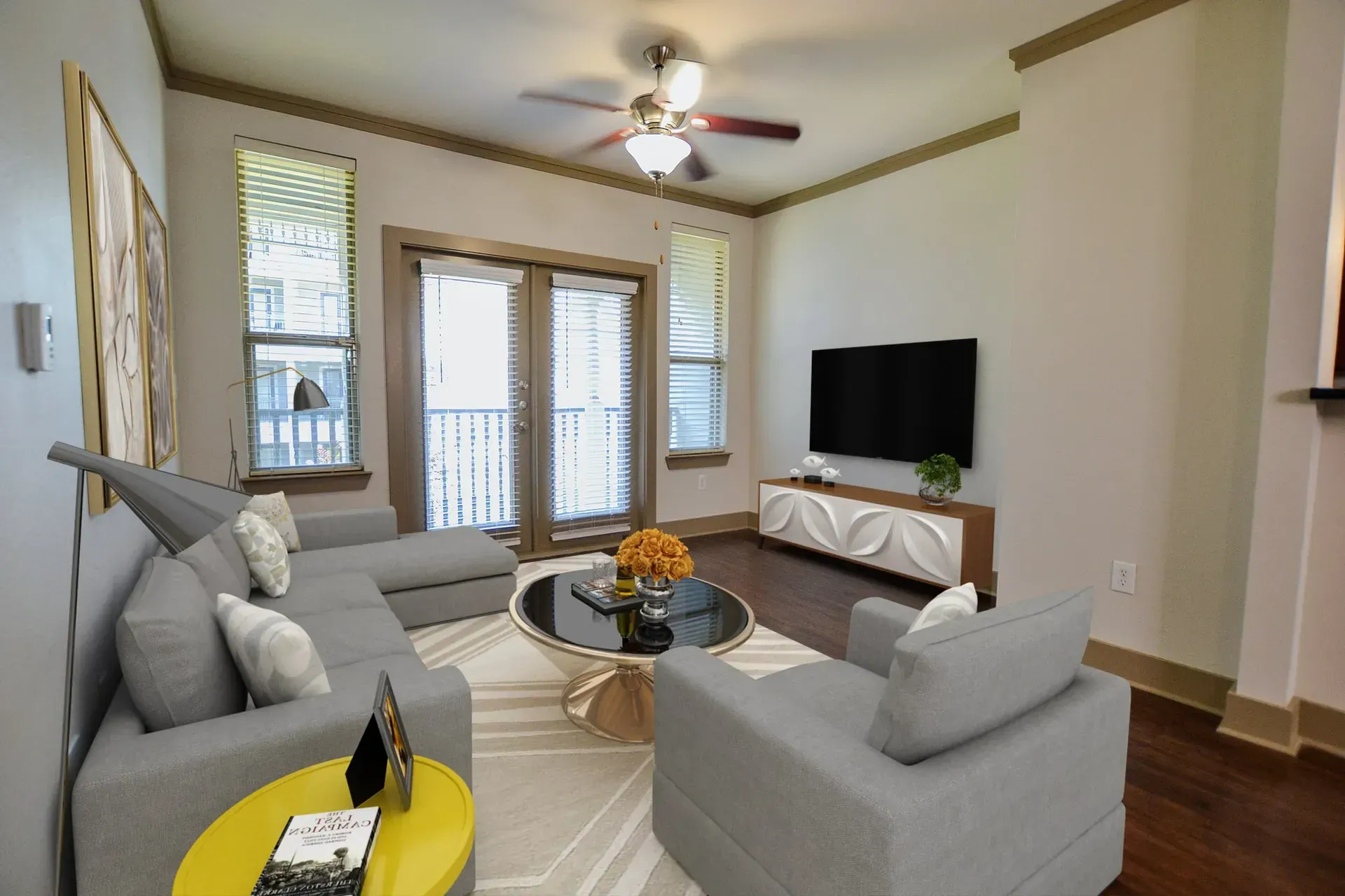 Living room with grey sectional, round coffee table, and balcony access.