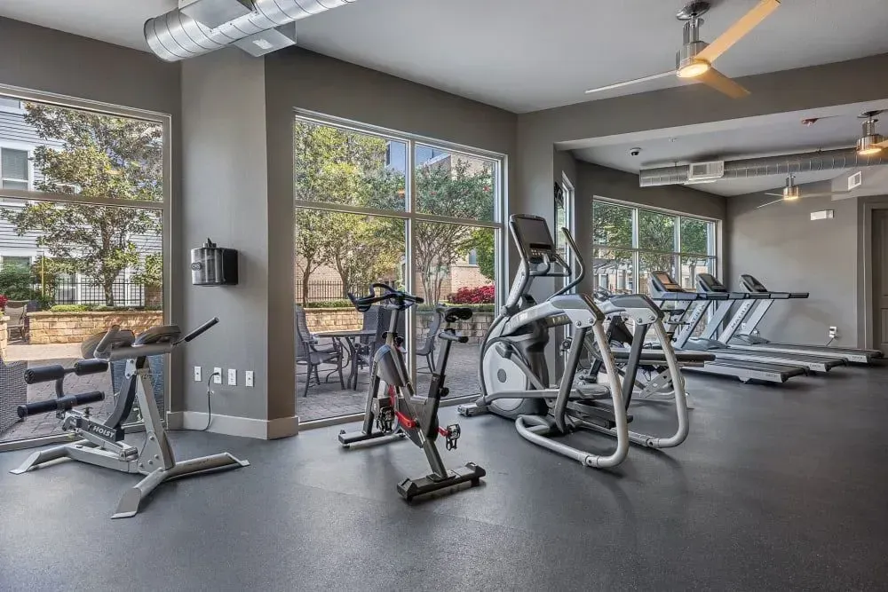Gym with exercise equipment, large windows, and outdoor patio view.