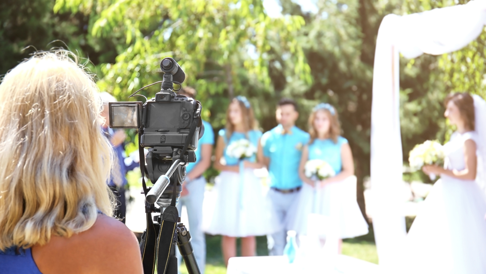 Videographer filming an outdoor Vermont wedding in the summer.