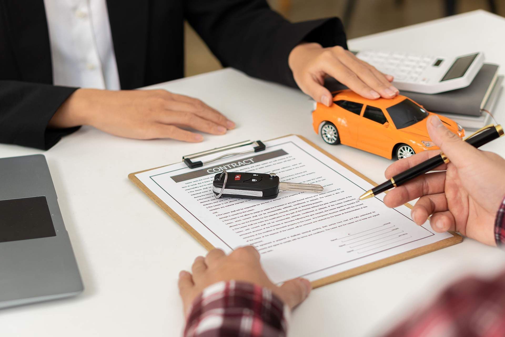 Hands examining toy car and paperwork during vehicle inspection meeting on a desk
