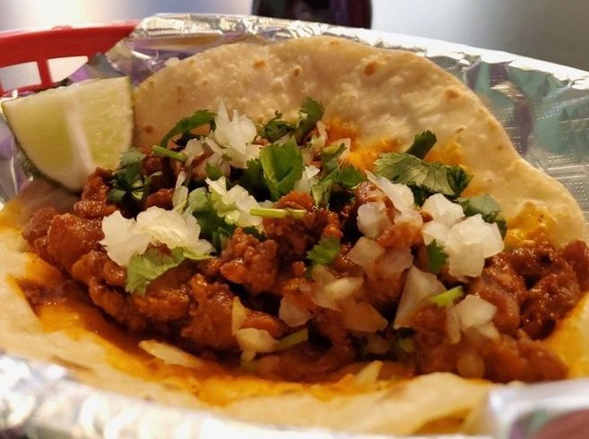 A close up of a taco on a wooden cutting board on a table.