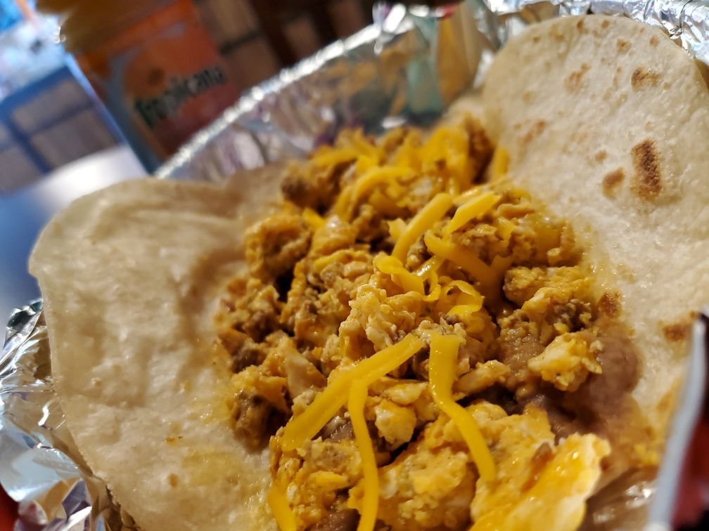 A person is holding a taco in their hands on a plate.