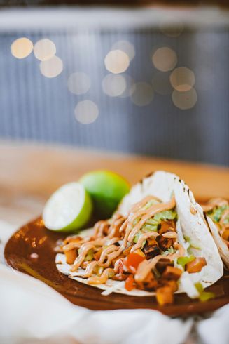 A close up of a taco on a wooden cutting board on a table.