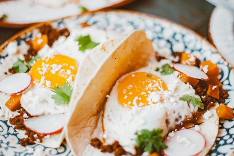 A close up of a plate of food with eggs and radishes on a table.