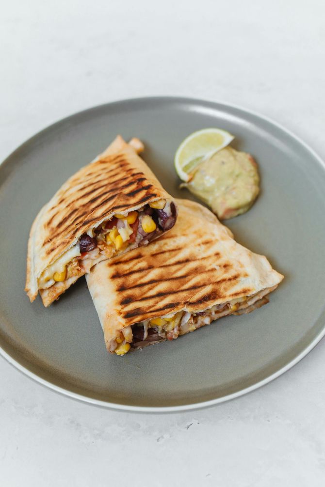 A close up of a quesadilla on a plate with a slice of lime.