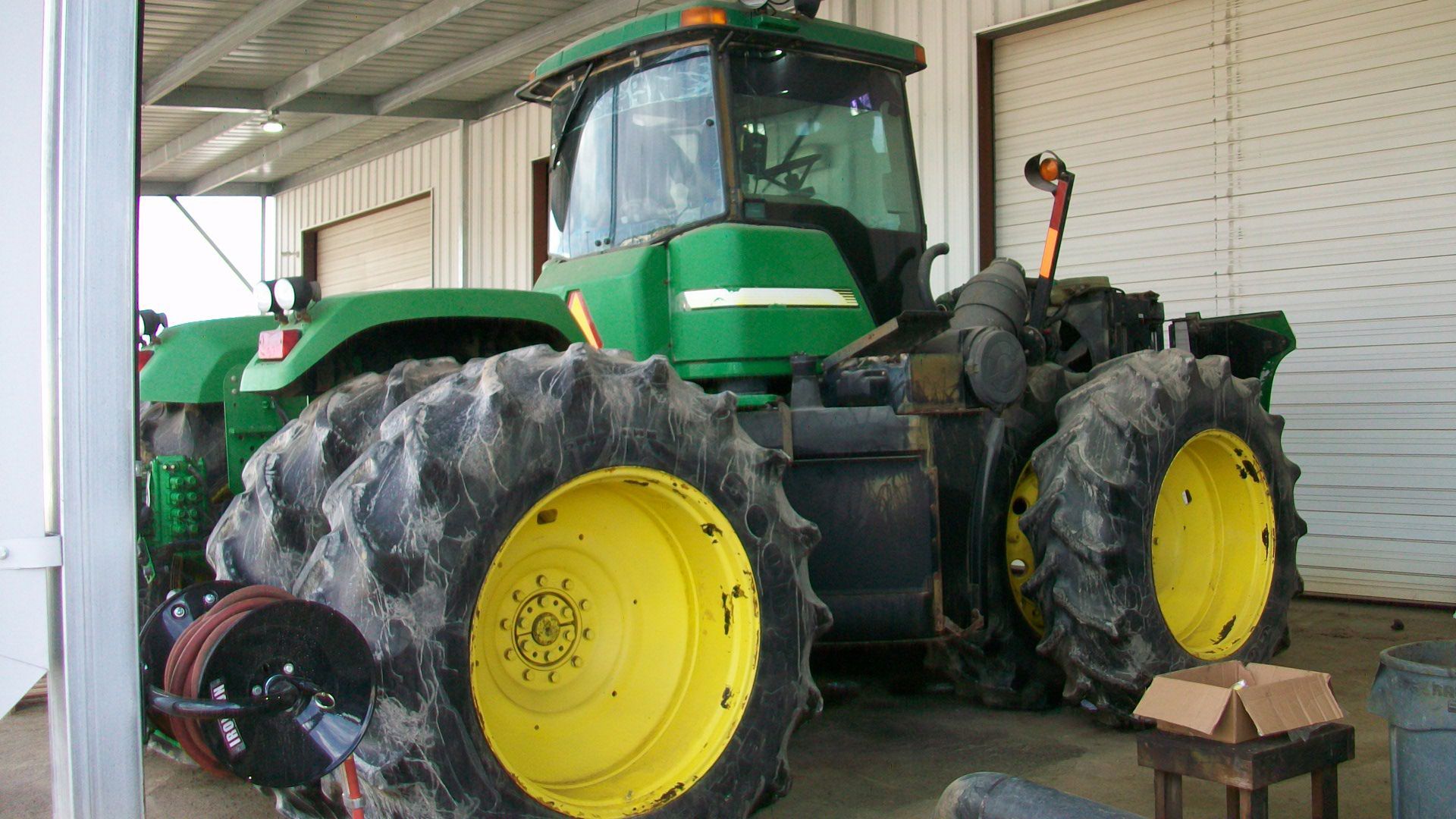 A green and yellow john deere tractor is parked in a garage.