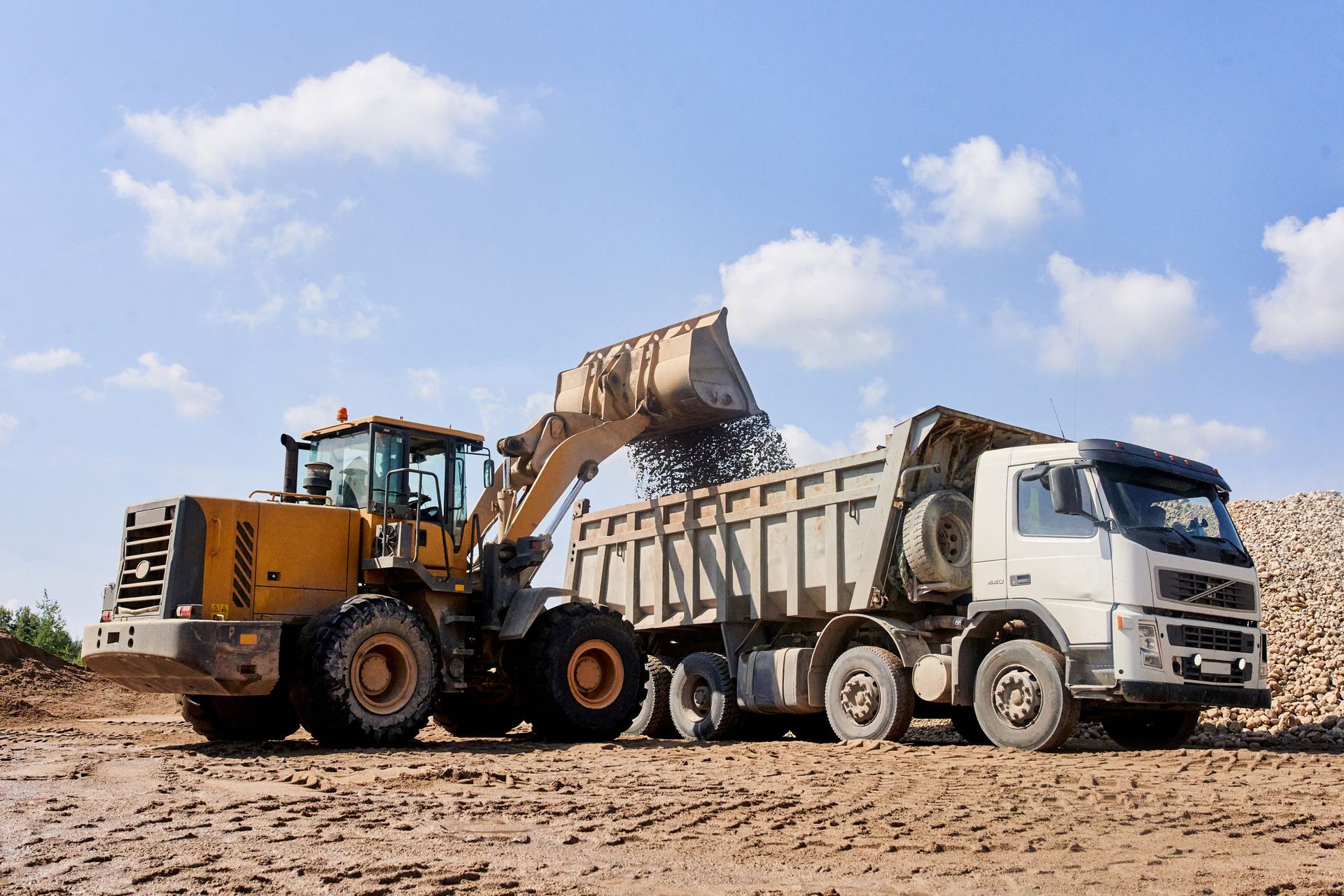 A bulldozer is loading dirt into a dump truck.