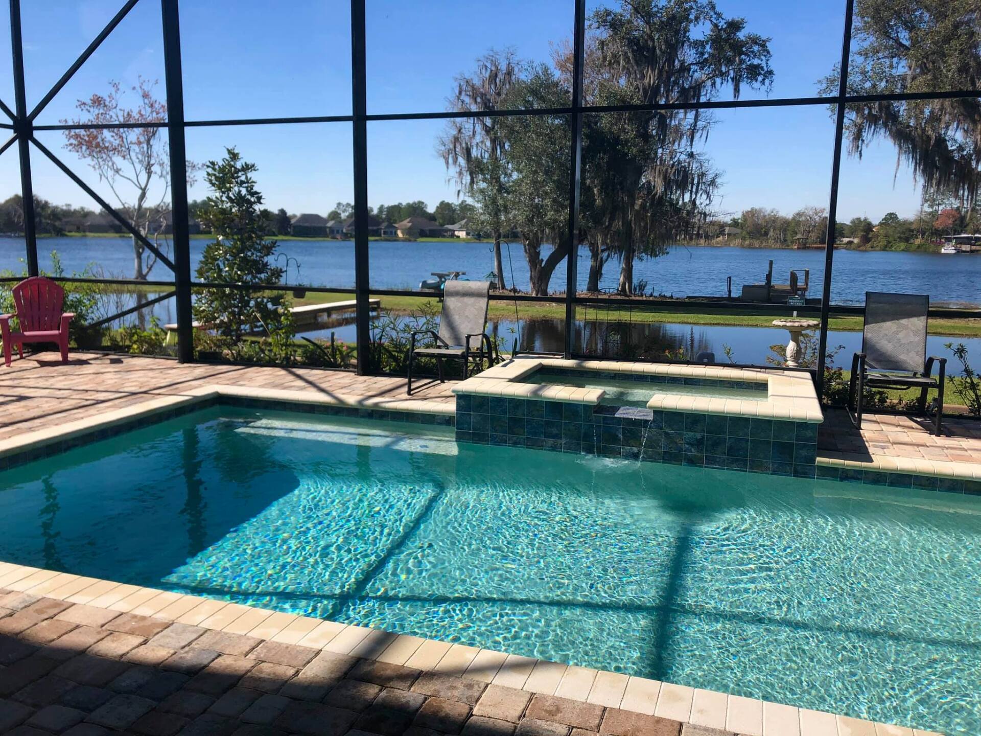 Pool with spa overlooking a lake; sunny, outdoor scene.