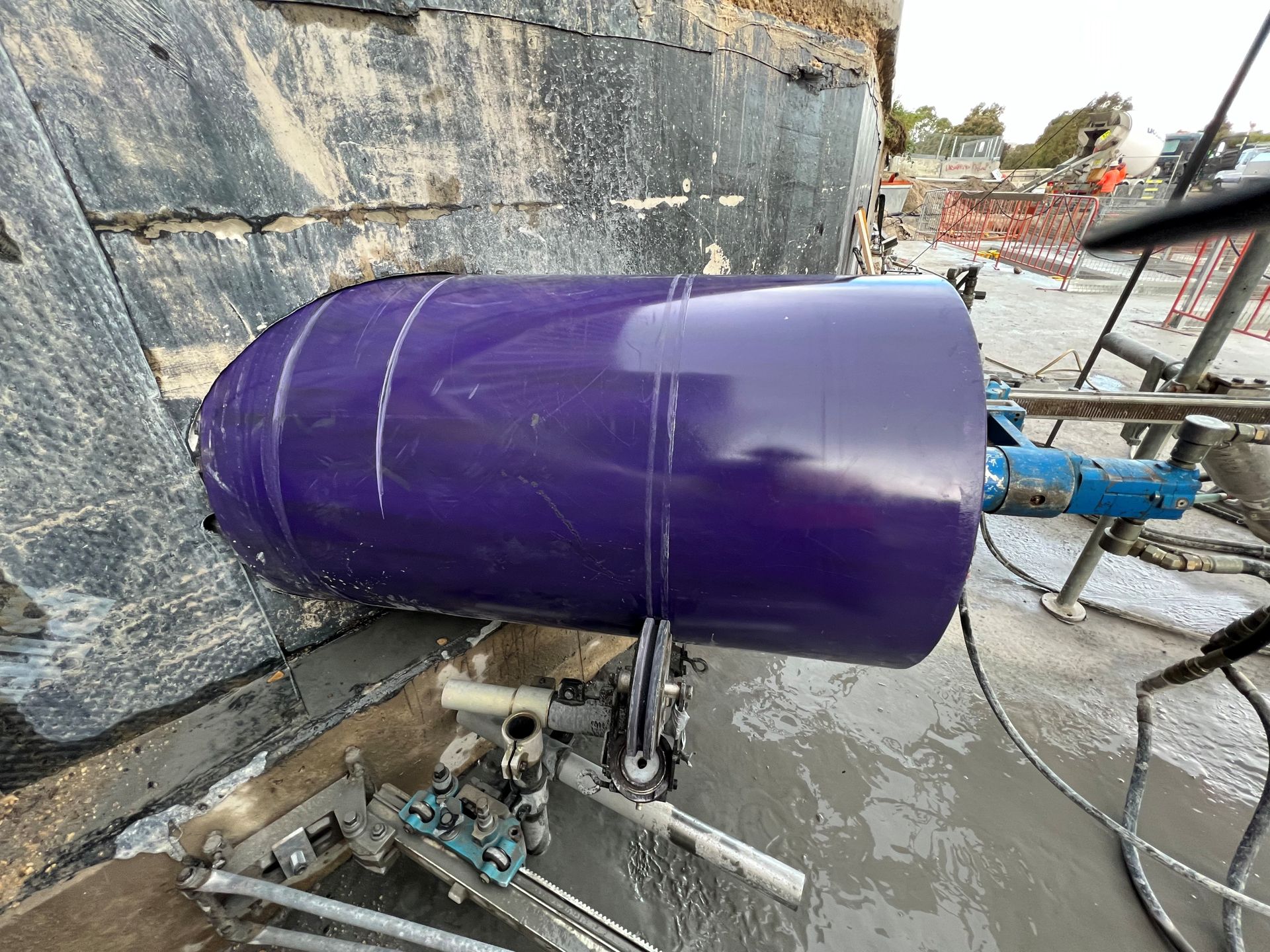 Man using a miter saw outdoors with a boy seated nearby. Sawing wood near trees.