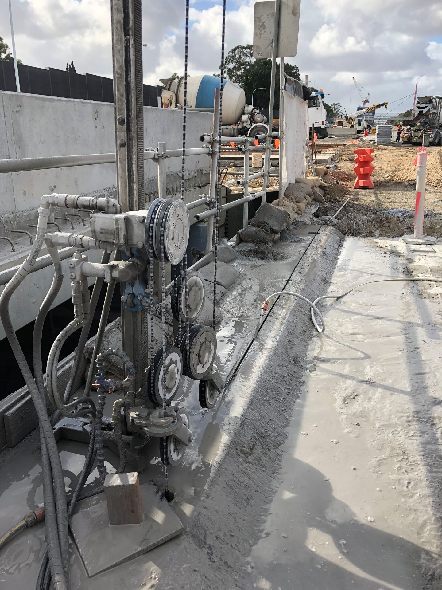 Man using a miter saw outdoors with a boy seated nearby. Sawing wood near trees.