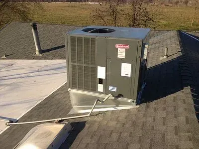 A large air conditioner is sitting on top of a roof.
