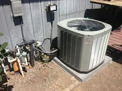A large air conditioner is sitting outside of a house.